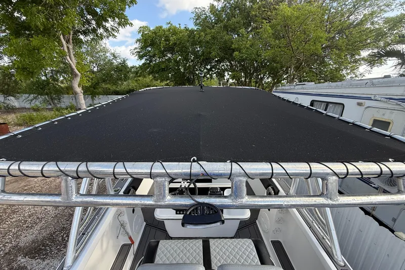 Slide: The Image of 1989 Wellcraft 302 Scarab boat with black canopy, surrounded by trees and trailers. - 66