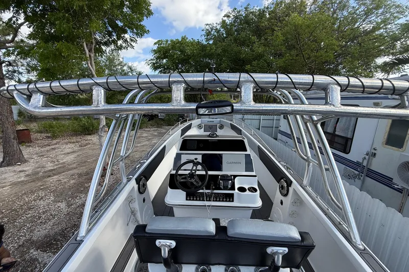 Slide: The Image of 1989 Wellcraft 302 Scarab boat cockpit with Garmin navigation, surrounded by trees and trailer. - 68