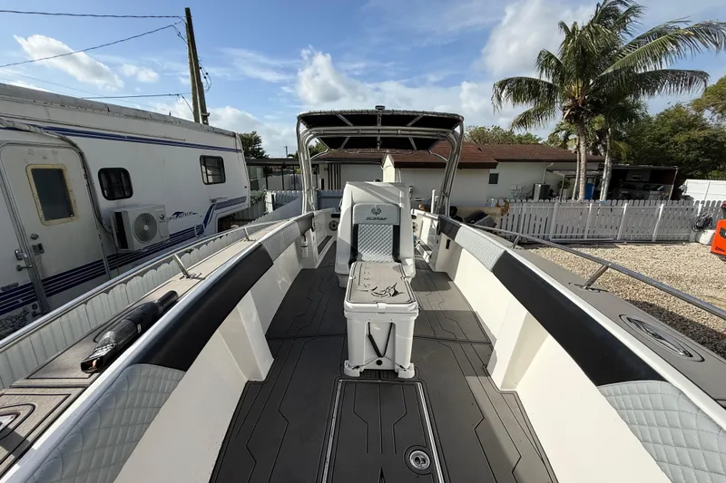 Slide: The Image of 1989 Wellcraft 302 Scarab boat interior with seating, docked near a trailer and palm trees. - 88