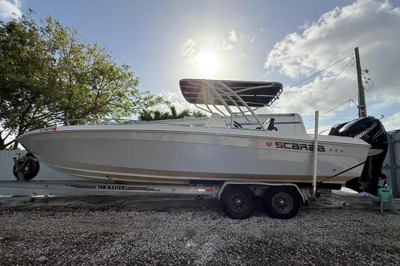 The Image of 1989 Wellcraft 302 Scarab boat on trailer, parked outdoors under a bright sky. - 2