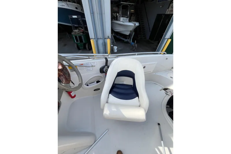 Slide: The Image of Interior of a 2006 Tahoe 222 boat with white seating and steering wheel. - 18