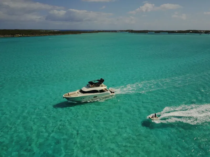 Slide: The Image of 2018 Monte Carlo Yachts MCY 65 cruising in turquoise waters with a jet ski nearby. - 16