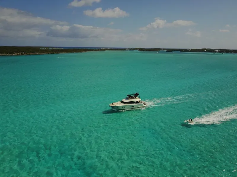 Slide: The Image of Monte Carlo Yachts MCY 65 (2018) cruising in turquoise waters with a jet ski nearby. - 21