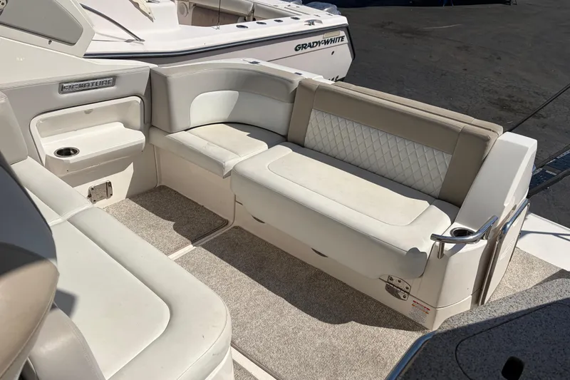 Slide: The Image of 2013 Chaparral 310 Signature boat interior with beige seating and carpeted flooring. - 14