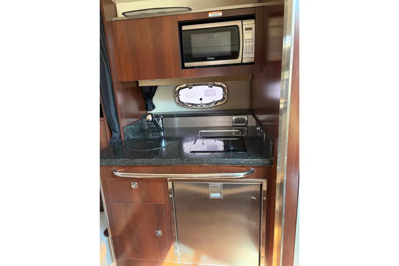 Slide: The Image of 2013 Chaparral 310 Signature yacht kitchenette with microwave, sink, and compact fridge. - 7