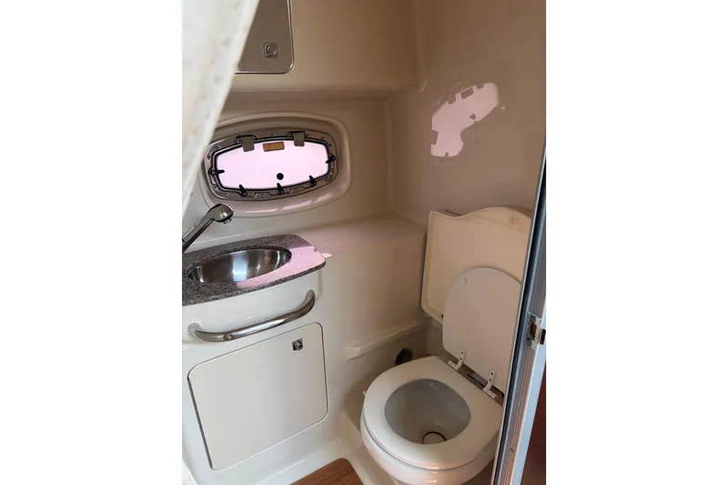 Slide: The Image of 2013 Chaparral 310 Signature boat bathroom with sink, toilet, and porthole window. - 8