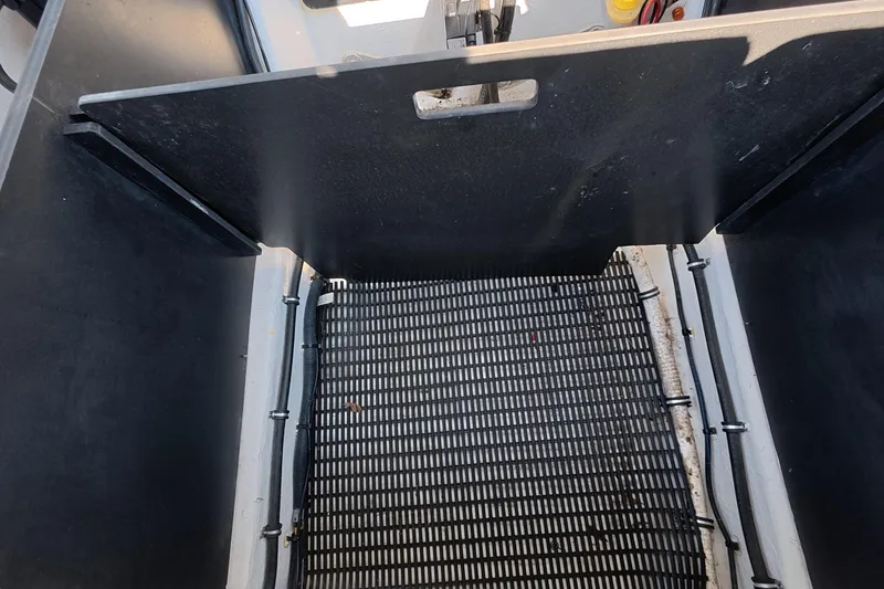 Slide: The Image of 2023 Monterey 305SS Super Sport boat storage compartment with black grid flooring. - 14