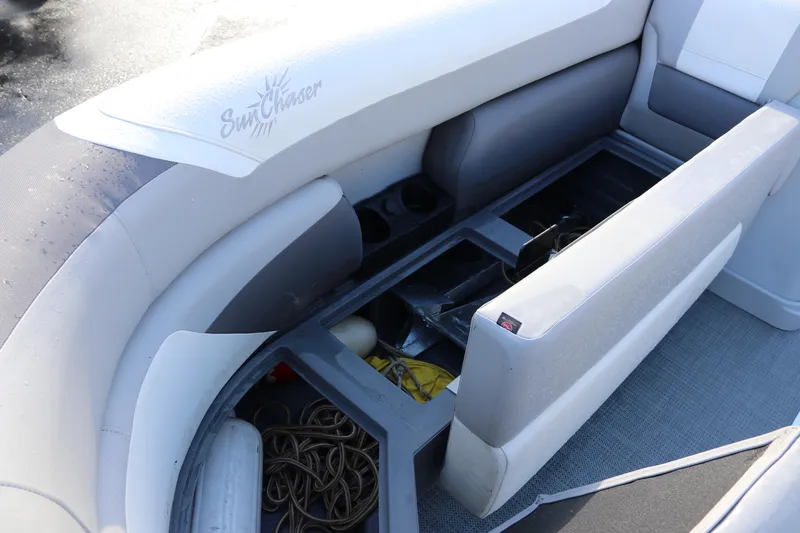 Slide: The Image of 2024 SunChaser Eclipse LR DH 25 Demo boat seat storage compartment open, revealing interior items. - 26