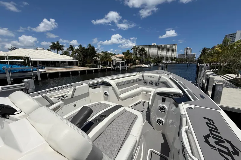 Slide: The Image of 2023 Fountain 38 SCX boat docked by waterfront homes under a clear blue sky. - 13