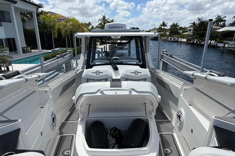 Slide: The Image of 2023 Fountain 38 SCX boat interior with open storage compartment, docked by a waterfront property. - 18