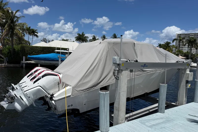 Slide: The Image of Covered 2023 Fountain 38 SCX boat on lift, with triple outboard engines, dockside view. - 29