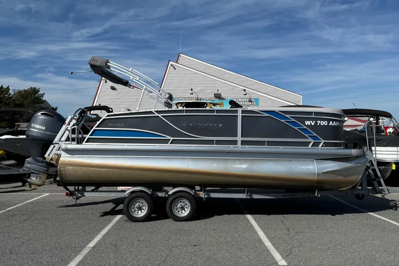 The Image of 2021 Godfrey Monaco 215 C pontoon boat on trailer, parked outdoors under clear sky. - 1