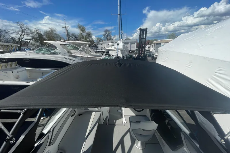 Slide: The Image of 2023 Yamaha Boats AR220 with black canopy, docked among other boats under a blue sky. - 11
