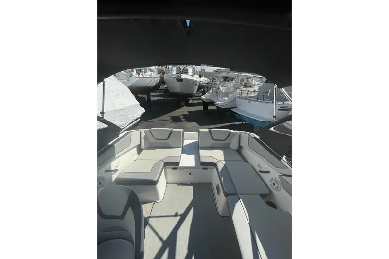 Slide: The Image of 2023 Yamaha Boats AR220 interior with seating, docked among other boats. - 12