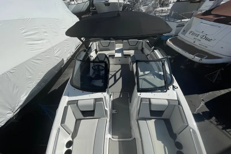 Slide: The Image of 2023 Yamaha Boats AR220 with sleek design and spacious seating, docked among other boats. - 14