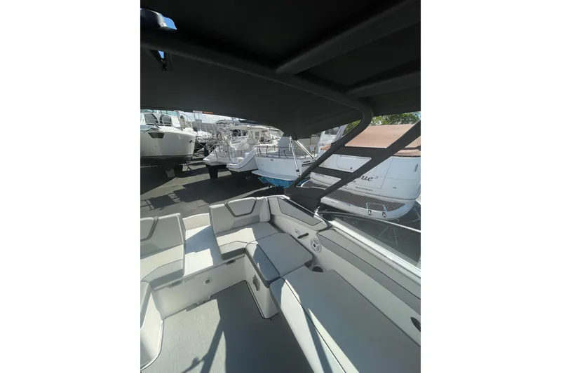 Slide: The Image of 2023 Yamaha Boats AR220 interior with seating and canopy, docked among other boats. - 7