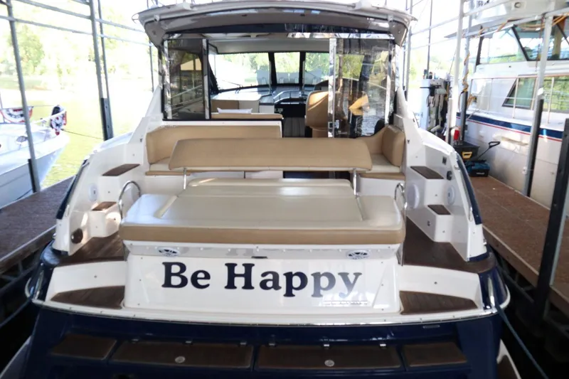 Slide: The Image of 2010 Regal 46 Sport Coupe yacht with "Be Happy" text on the back, docked in a marina. - 12