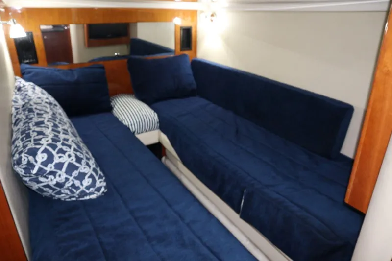 Slide: The Image of Interior cabin of 2010 Regal 46 Sport Coupe with blue bedding and wood accents. - 25