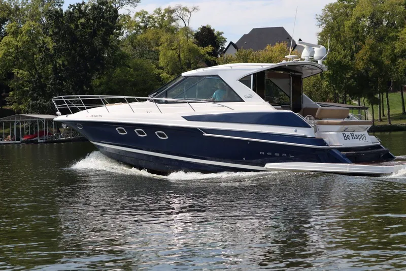 Slide: The Image of 2010 Regal 46 Sport Coupe cruising on a serene lake with lush greenery. - 4