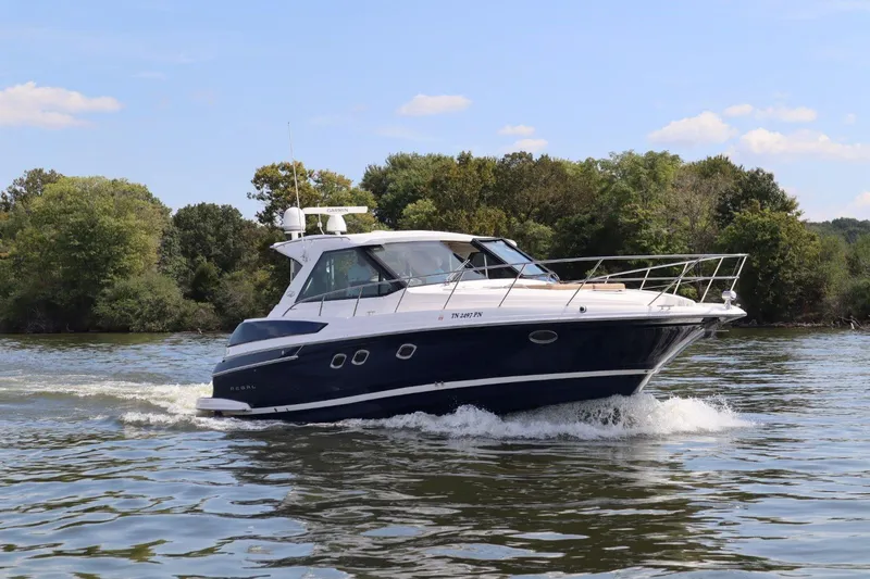 Slide: The Image of 2010 Regal 46 Sport Coupe cruising on a scenic lake with lush greenery. - 5