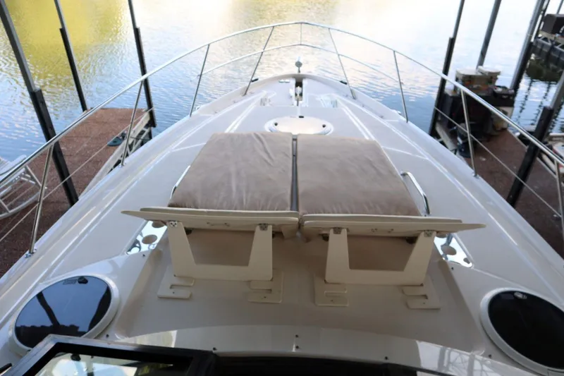 Slide: The Image of 2010 Regal 46 Sport Coupe yacht bow with cushioned seating, docked by calm water. - 9