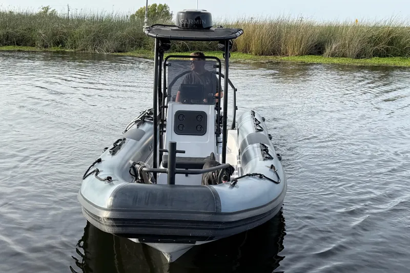 Slide: The Image of 2023 Inmar 660R-PT-PR inflatable boat navigating calm waters with grassy shoreline. - 18