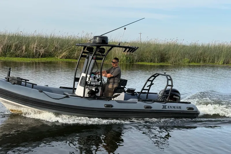 Slide: The Image of 2023 Inmar 660R-PT-PR boat cruising on a calm river with reeds in the background. - 21