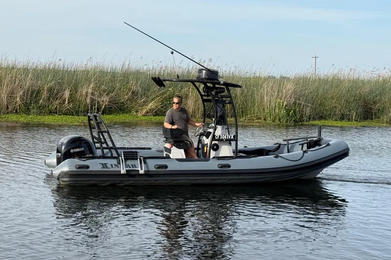 Slide: The Image of 2023 Inmar 660R-PT-PR boat cruising on a calm waterway with reeds in the background. - 8