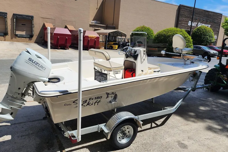 Slide: The Image of 2024 Carolina Skiff EV180 Sea Skiff on trailer, featuring Suzuki outboard motor. - 2