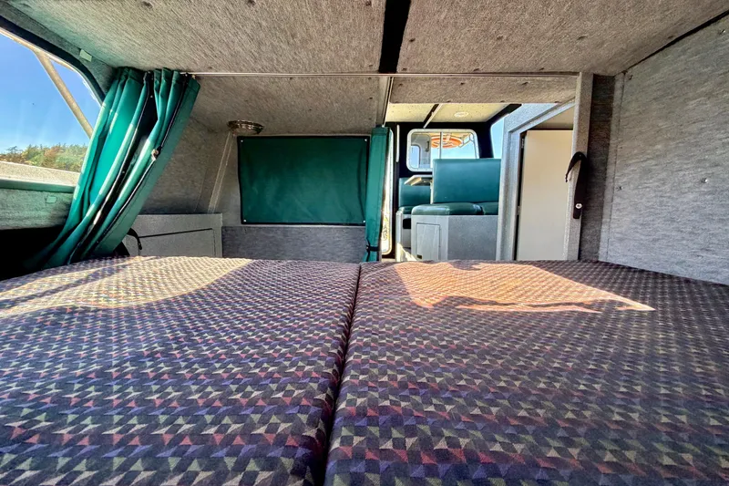 Slide: The Image of Interior of a 2001 Maxweld Maxcat boat with patterned bedding and teal curtains. - 33