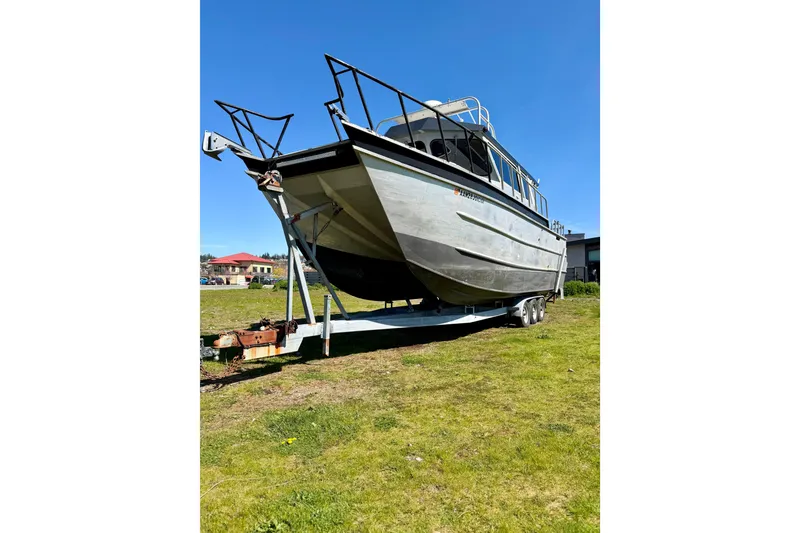 Slide: The Image of 2001 Maxweld Maxcat boat on trailer, parked on grassy area under clear blue sky. - 37