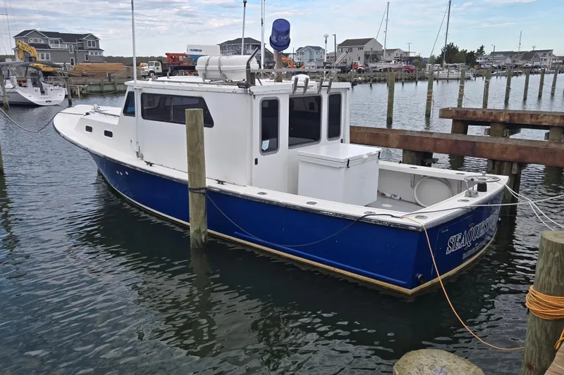 The Image of 1977 JC 31 Casco Bay boat docked in a marina, featuring a blue and white exterior. - 0