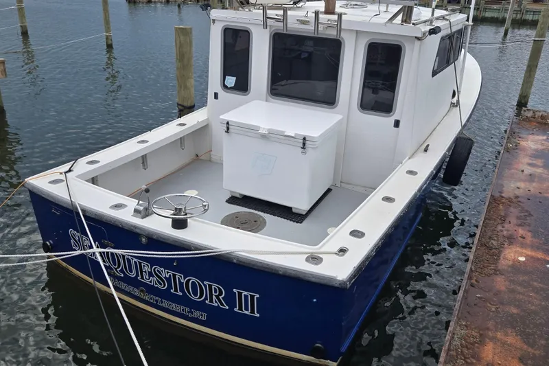Slide: The Image of 1977 JC 31 Casco Bay boat docked, named "Sequestor II," with a white deck and blue hull. - 25