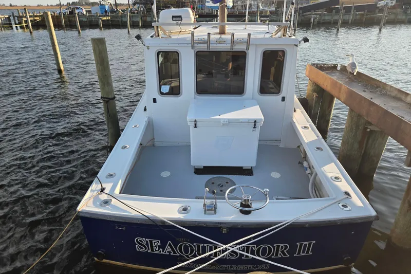 Slide: The Image of 1977 JC 31 Casco Bay boat docked, rear view with open deck and seagull nearby. - 4