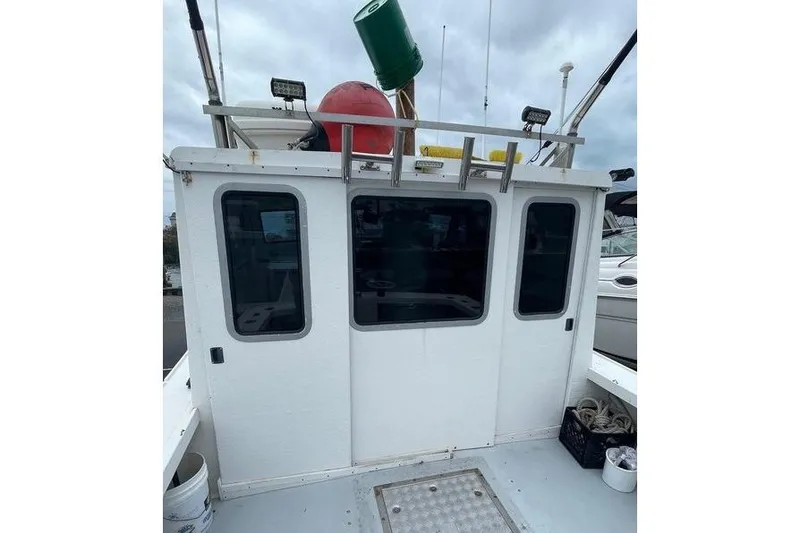 Slide: The Image of 1977 JC 31 Casco Bay boat cabin with equipment on roof, docked under cloudy sky. - 5