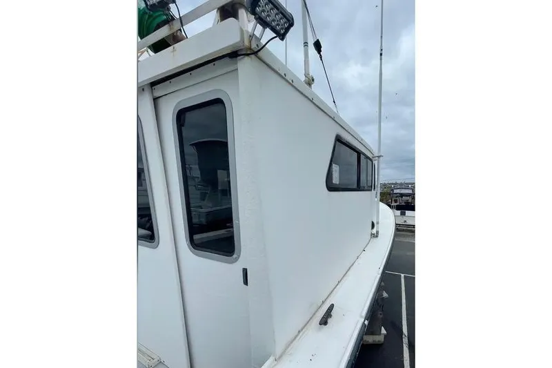 Slide: The Image of 1977 JC 31 Casco Bay boat, white exterior, docked under cloudy skies. - 9