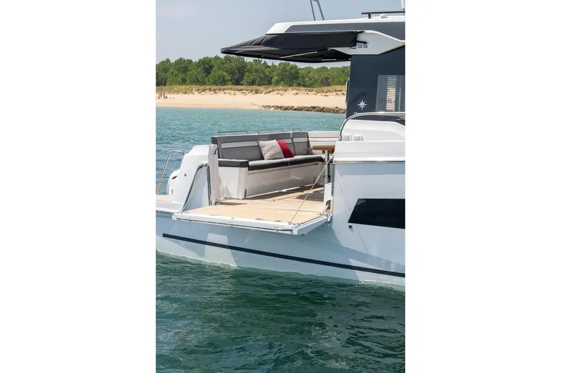 Slide: The Image of Manufacturer Provided Image: 2025 Jeanneau NC 1295 Coupe yacht with open deck, docked near a sandy beach. - 4