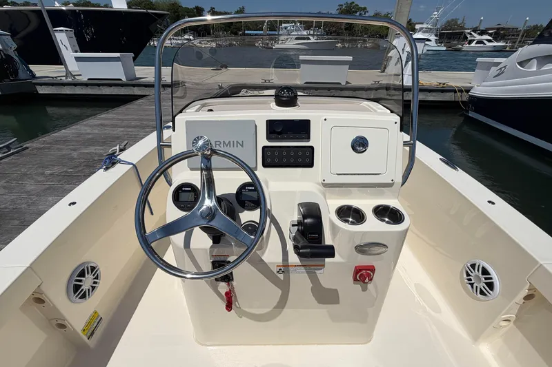 Slide: The Image of 2026 Scout 188 Sportfish boat dashboard with steering wheel and controls at marina. - 5