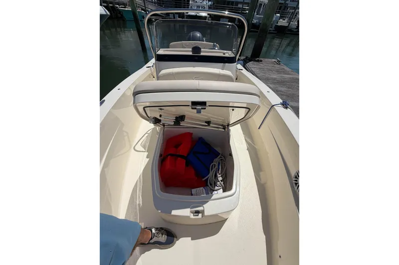 Slide: The Image of 2026 Scout 188 Sportfish boat with open storage compartment, docked at marina. - 8