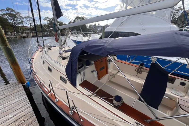 Slide: The Image of Sailboat Island Packet 350, 2000 model, docked with blue canopy and wooden deck. - 2