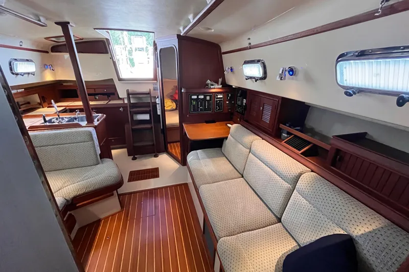 Slide: The Image of Interior of a 2000 Island Packet 350 sailboat, featuring cozy seating and a compact kitchen area. - 6