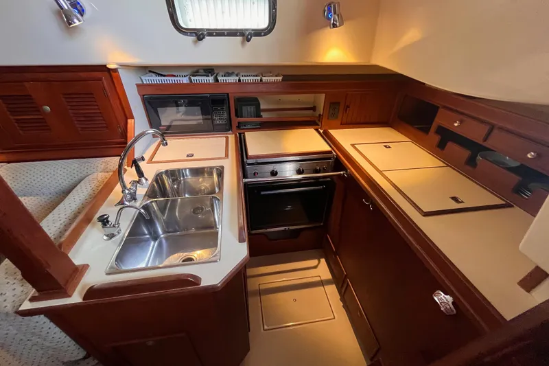 Slide: The Image of Island Packet 350 yacht kitchen, 2000 model, featuring sink, stove, and wooden cabinetry. - 8