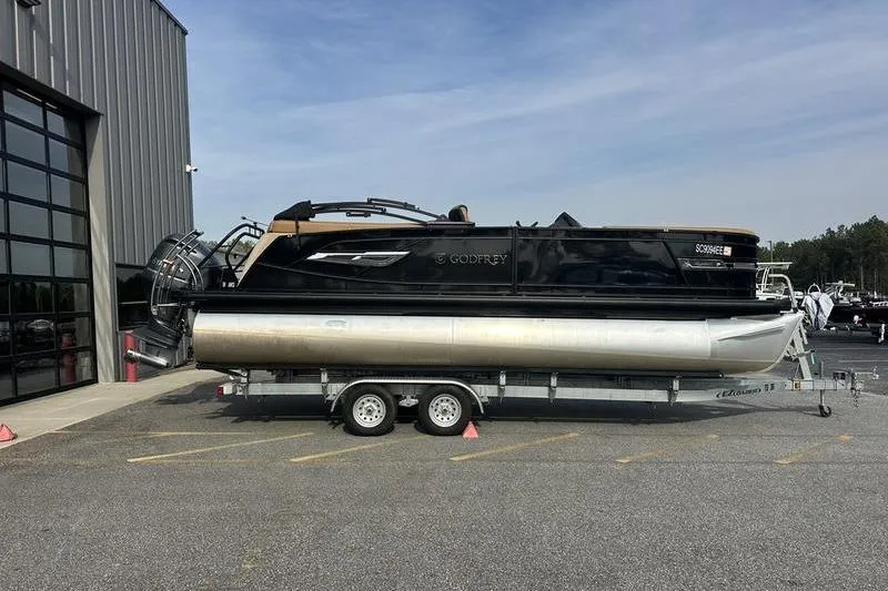 Slide: The Image of 2024 Godfrey AquaPatio 235 ULC iMPACT pontoon boat on trailer outside showroom. - 2