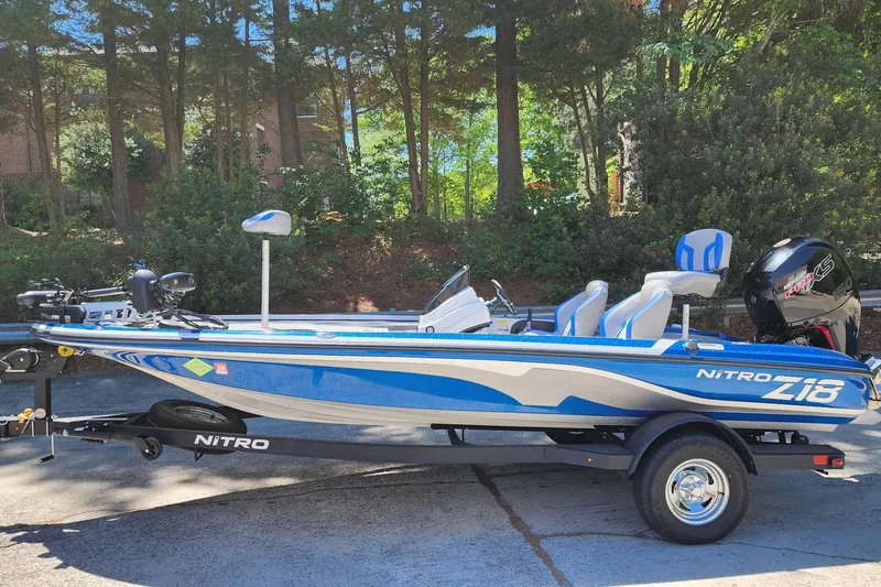 The Image of 2025 Nitro Z18 Pro boat on trailer, blue and white design, parked outdoors. - 0