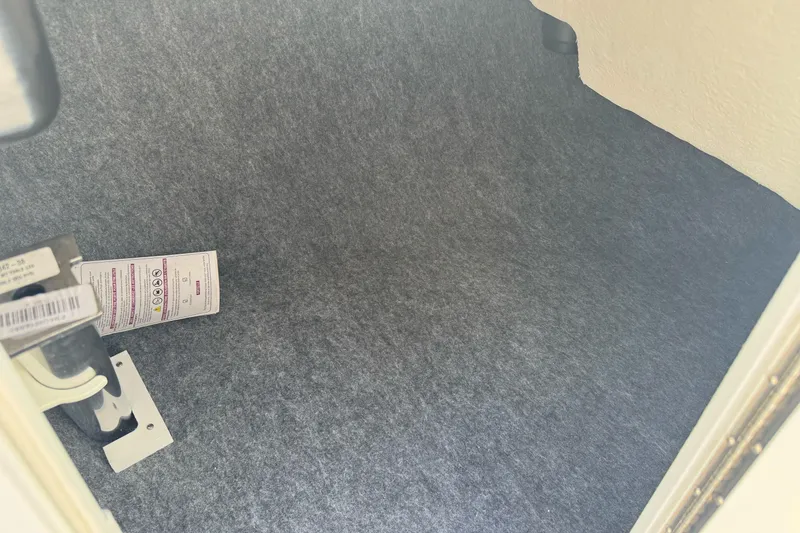 Slide: The Image of Interior storage compartment of 2024 Yamaha Boats AR190, featuring carpeted lining and safety instructions. - 21