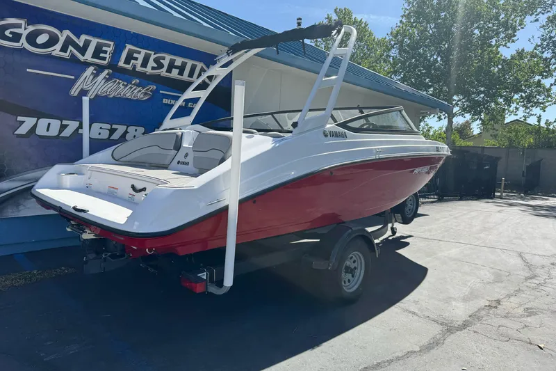 Slide: The Image of 2024 Yamaha Boats AR190 in red and white, parked on a trailer outside a marine shop. - 3