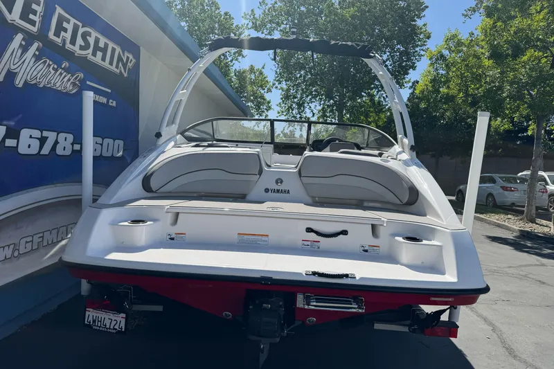 Slide: The Image of 2024 Yamaha Boats AR190 displayed outdoors, rear view with trees and building in background. - 9