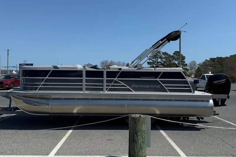 Slide: The Image of 2026 Berkshire 22CL2 CTS pontoon boat parked in a lot, featuring a Mercury engine. - 5
