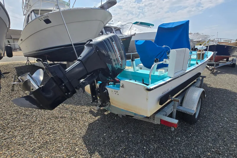 Slide: The Image of 1972 Boston Whaler 17 Montauk boat on trailer, featuring outboard motor, parked on gravel. - 9
