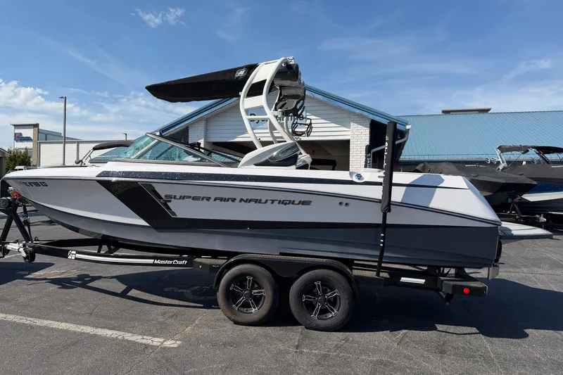 The Image of 2015 Nautique Super Air Nautique 230 boat on trailer, parked outdoors. - 1